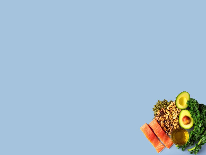 Fish, leafy greens, avocado and nuts on a light blue surface