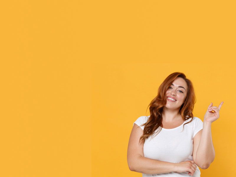 A woman smiling with long brown hair and waring a white shirt in front of a yellow background