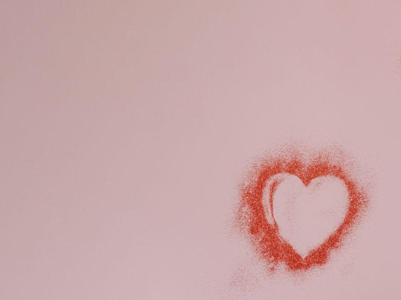 A heart formed with red powder on a pinkish-purple surface