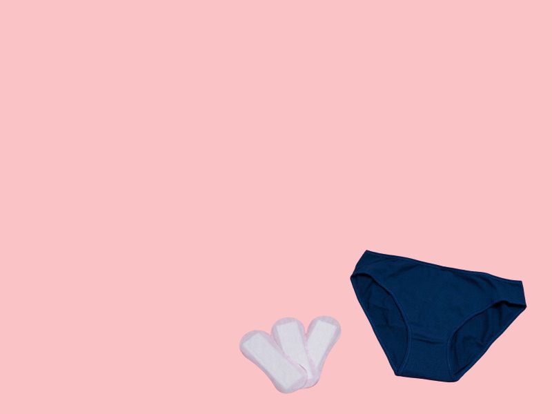 Dark blue underwear and 3 menstrual pads on a pink background