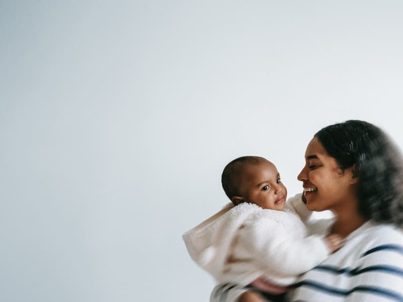 Smiling woman holding a baby, sharing a warm, affectionate moment.