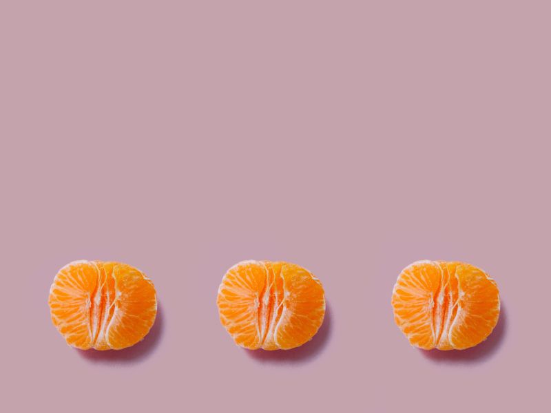 3 halved oranges on a mauve background