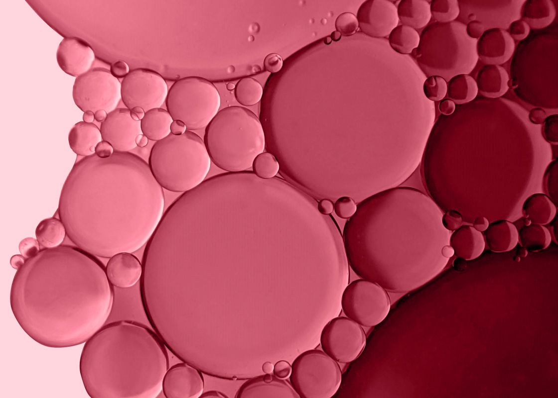 a light pink background with a mix of dark pink bubbles on the surface