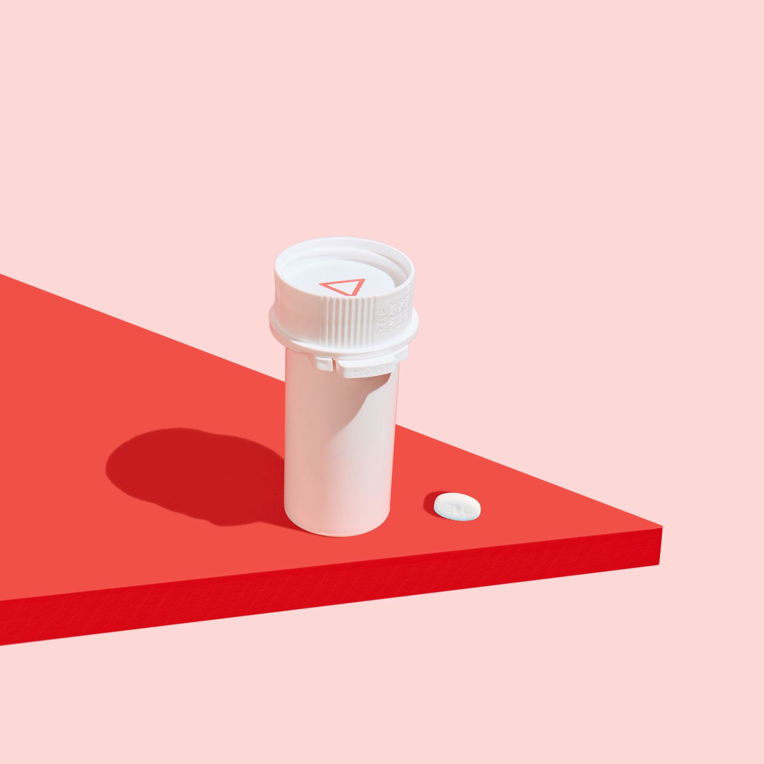 Wisp pill vial with a Norethindrone Acetate pill next to it on a red surface with a pink background
