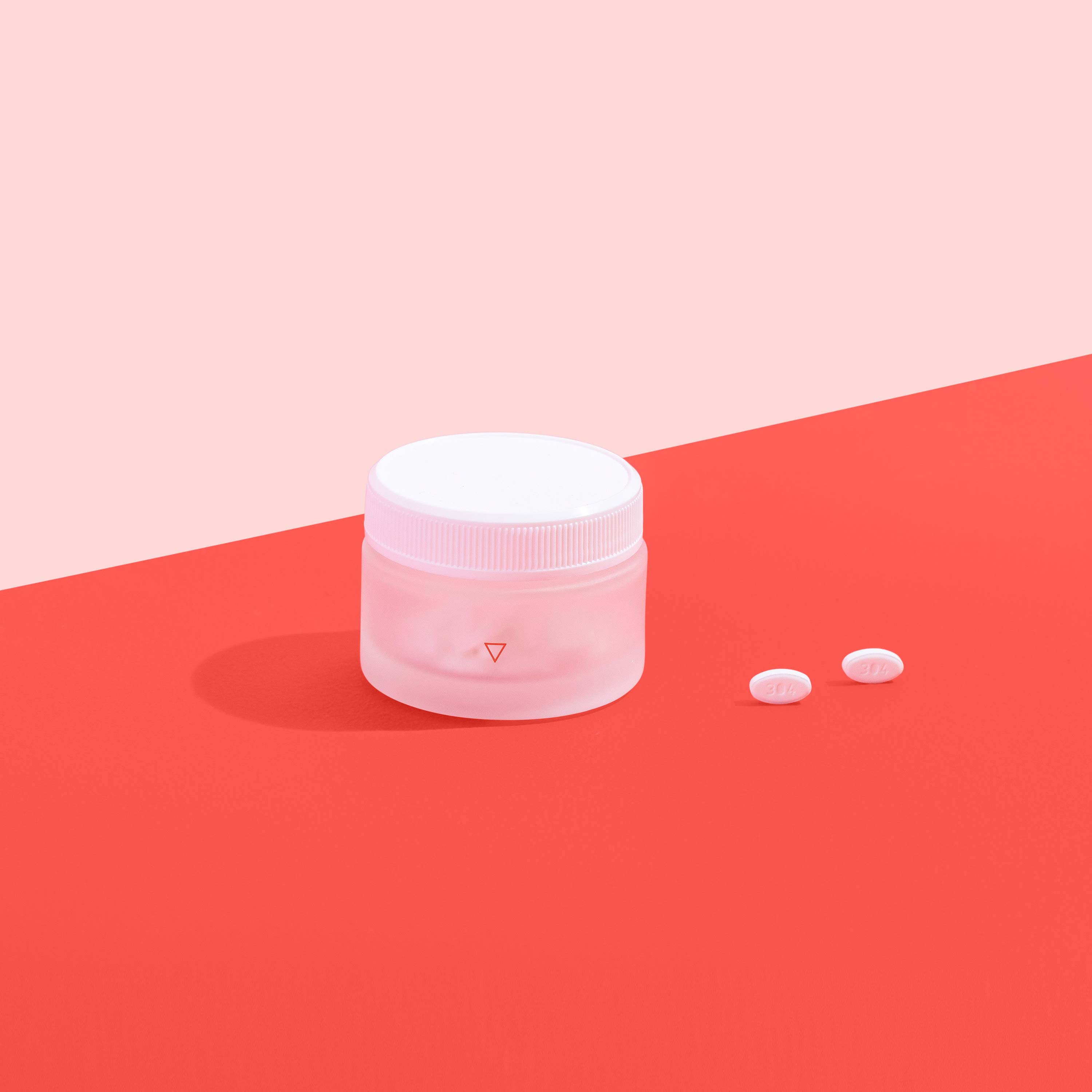 Norethindrone delay your period medication in a circular container in front of a red background