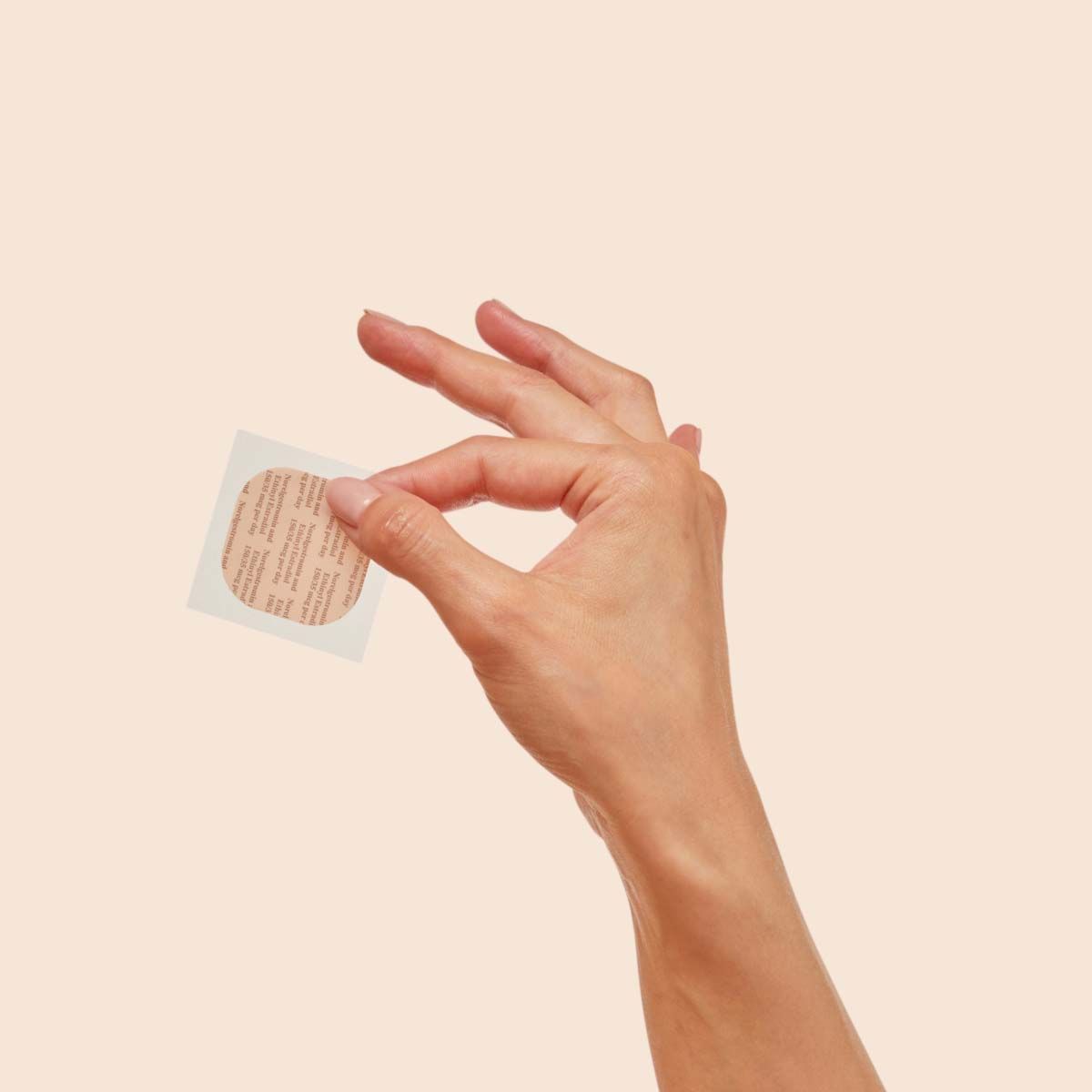 A woman's hand holding a patch in front of a cream background