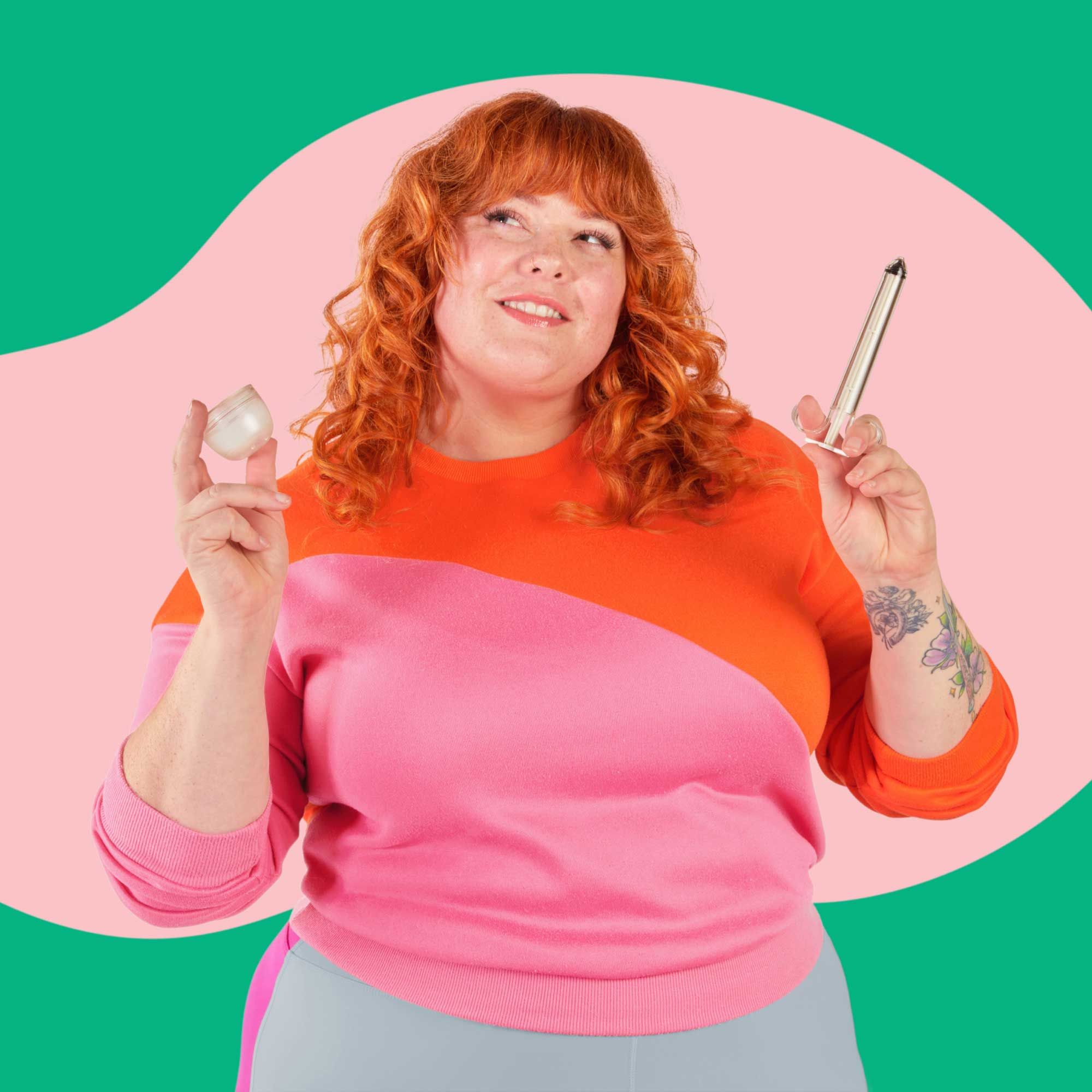 A woman wearing a read and pink sweater is holding the PherDal Syringe and collection cup