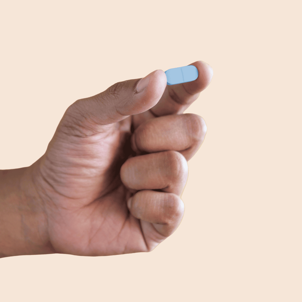 hand holding blue pill between thumb and pointer fingers
