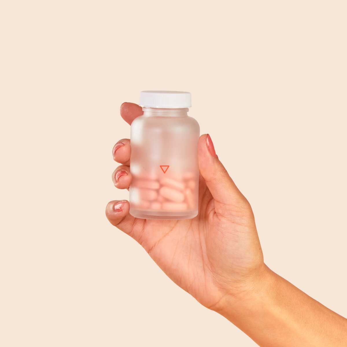 Wisp prenatal vitamins in a person's hand with a cream background