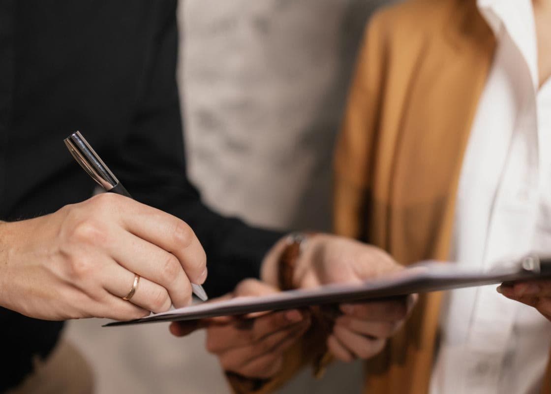 Two professional women doing paperwork on a clipboard