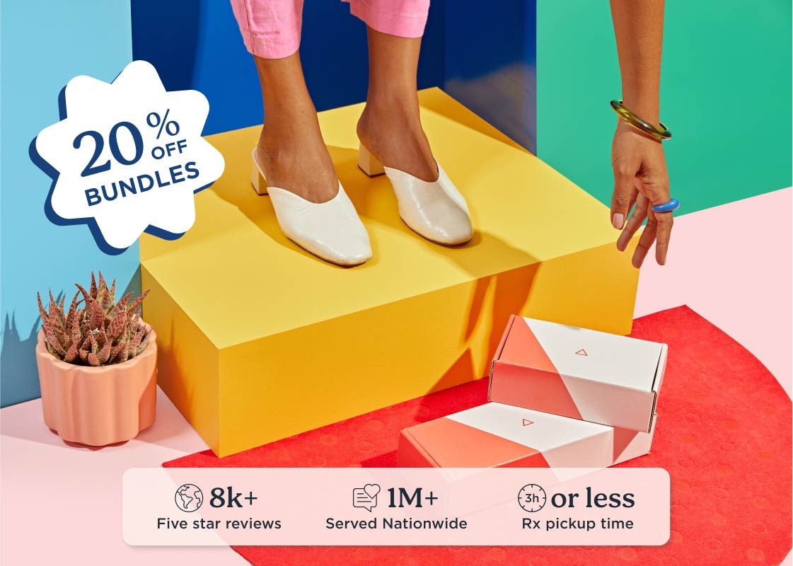 A woman standing on a colorful door step is reaching for Wisp shipping boxes