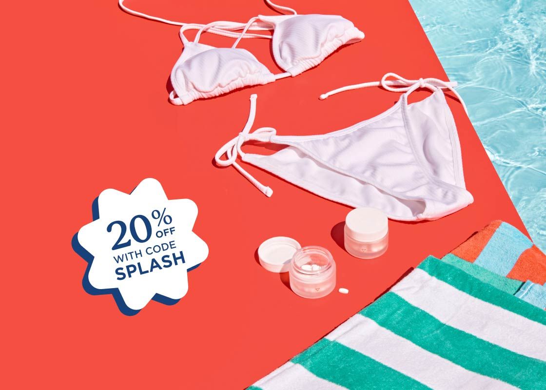 A white bikini, striped towels, and Wisp medications sitting on a red surface next to a pool
