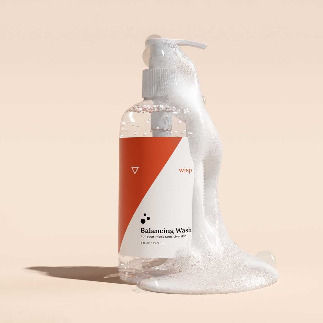 Bottle of Wisp Balancing Wash with foam spilling out on a cream surface