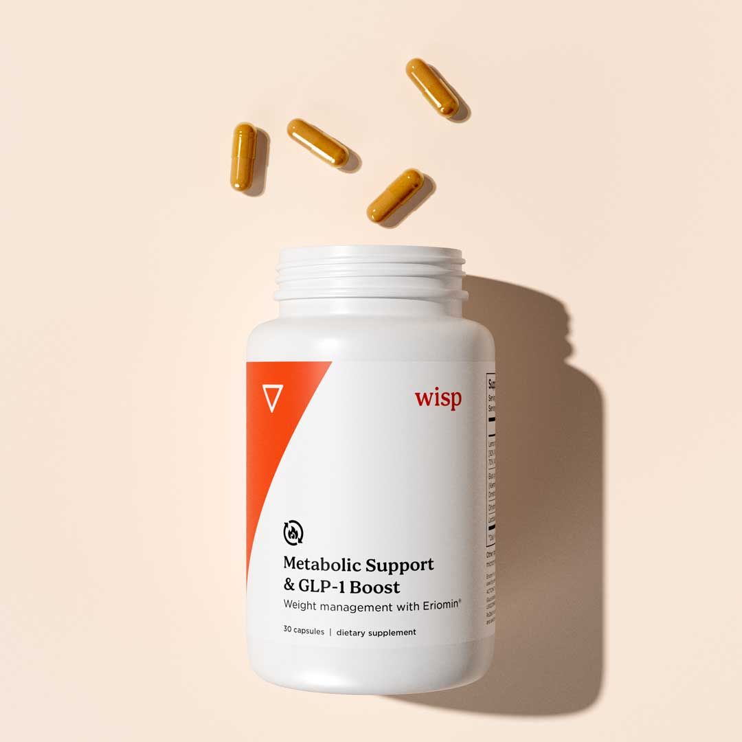 A bottle of Wisp Metabolic Support capsules with pills spilling out on a cream surface