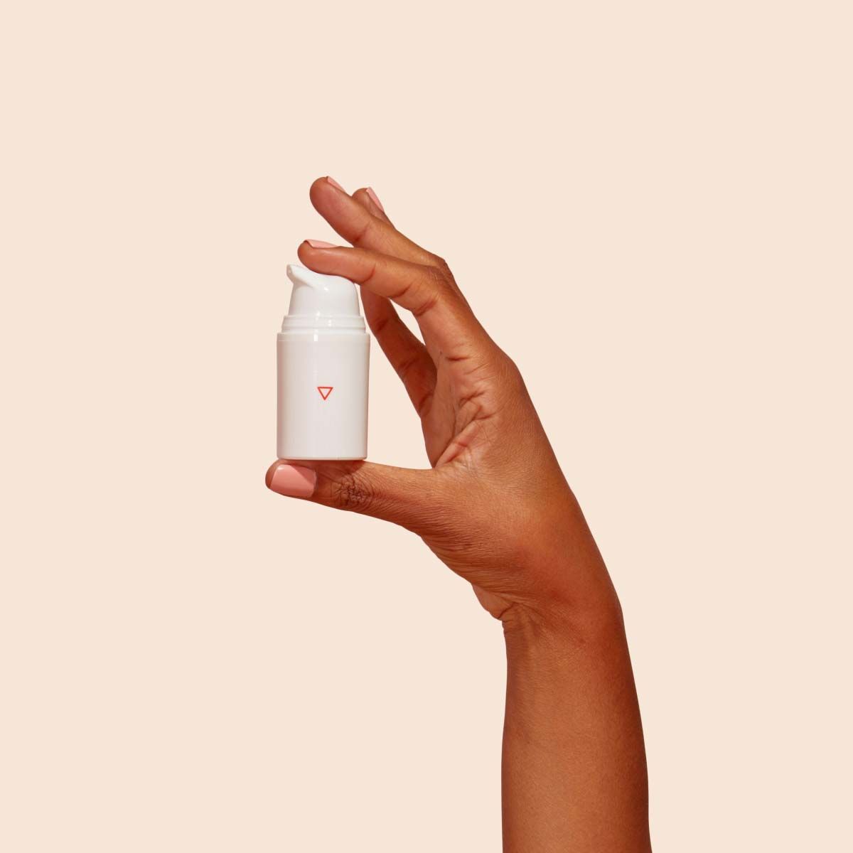 A Wisp pump bottle on a red surface with a cream background