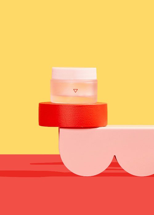 A small glass pill jar balancing on colorful abstract shapes with a yellow and red background
