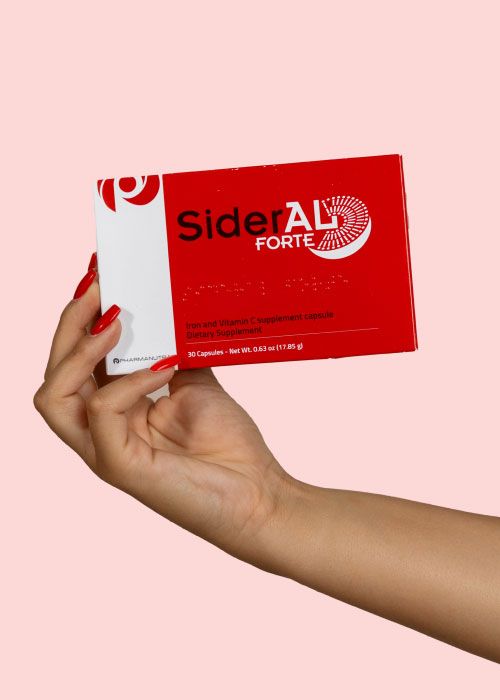 A woman's hand holding a box of SiderAL Forte Sucrosomial Iron