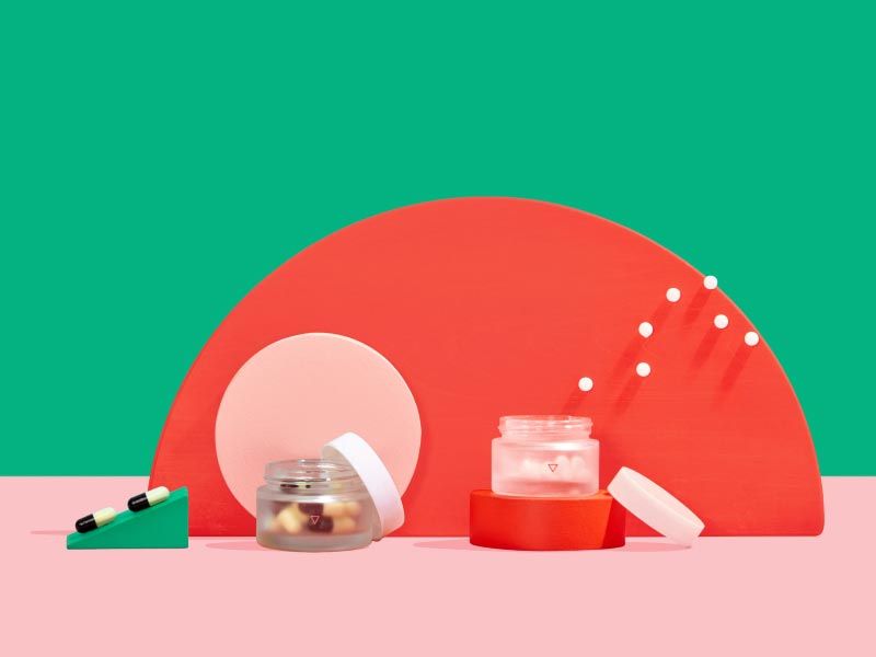 Two small Wisp glass jars with pills floating out on colorful abstract shapes with a green and pink background
