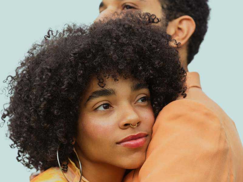 Couple embracing looking ahead against a plain sky background