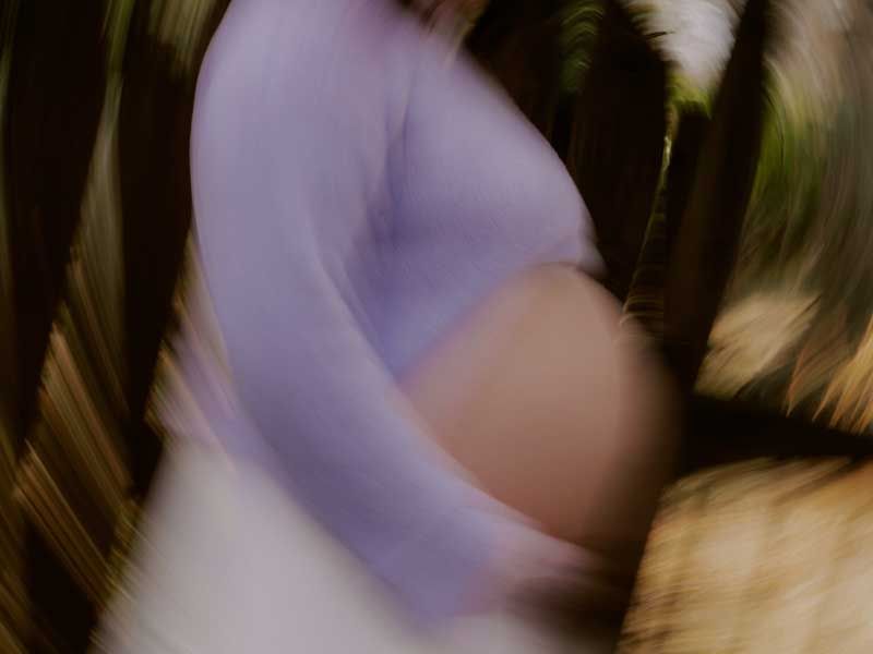 Soft blurred close up of a pregnant torso in motion.