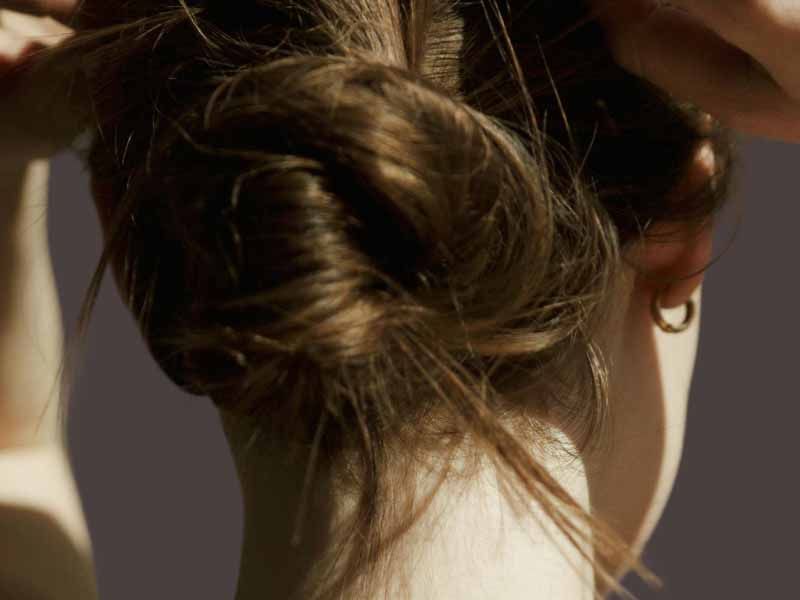 Close up of back of woman's head as she ties her hair up