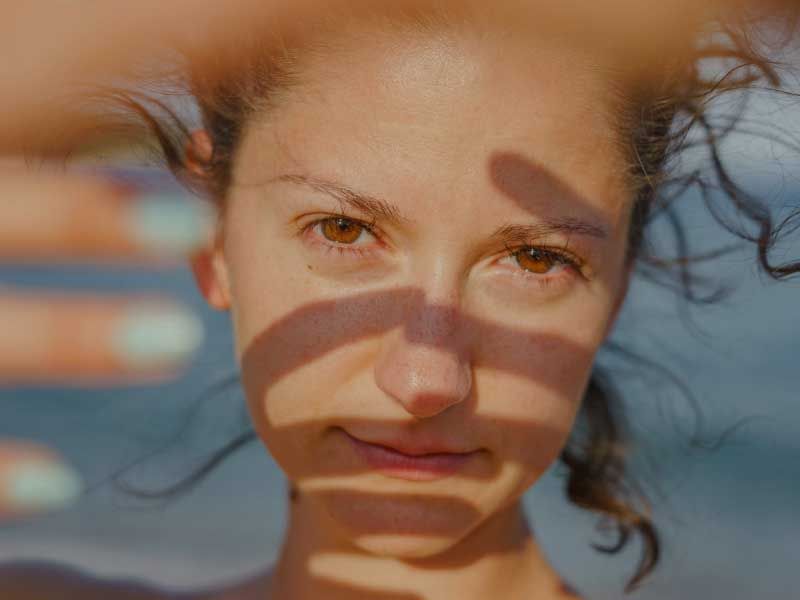 Close-up portrait of a woman with wet hair and warm brown eyes in natural sunlight.