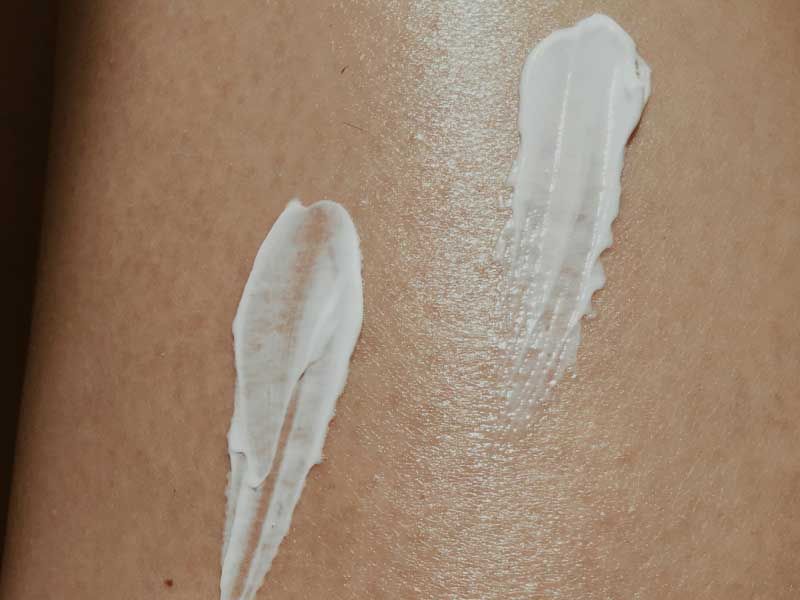 Two swipes of white moisturizer or lotion on bare skin.