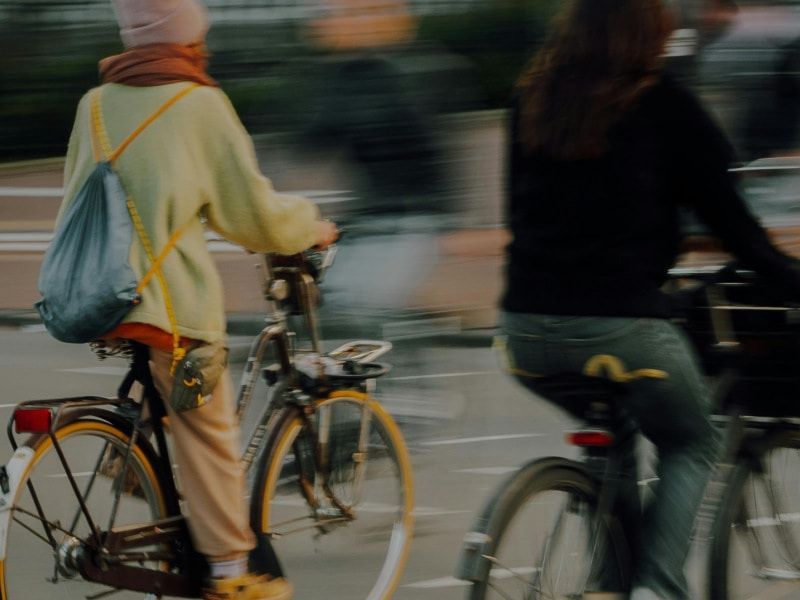A person riding a bicycle through an urban street, captured with motion blur conveying a sense of speed and movement.
