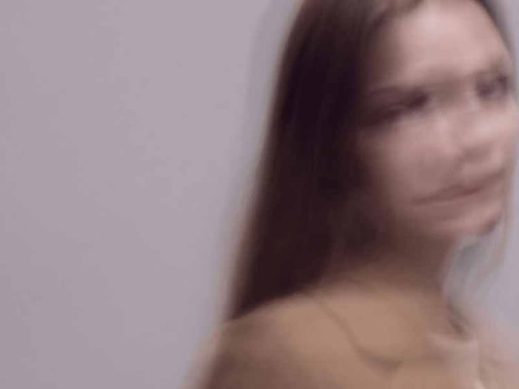 Soft-focus portrait of a person in motion against a light background