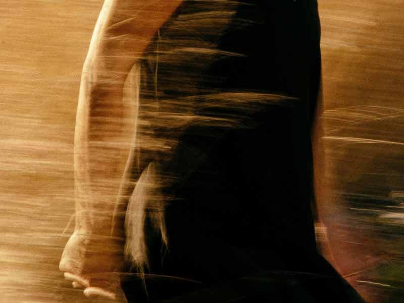 Motion-blurred figure walking through tall grass or a field