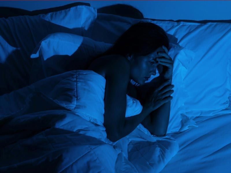 A woman laying a awake in bed with moody lighting