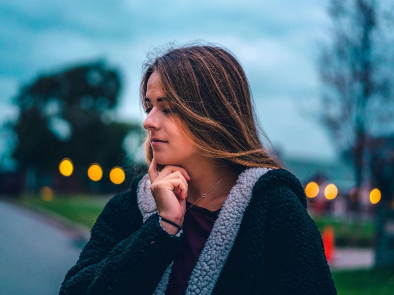 A woman looking contemplative while outside with stormy weather