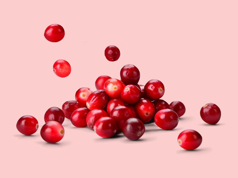 a pile of cranberries on a pink background