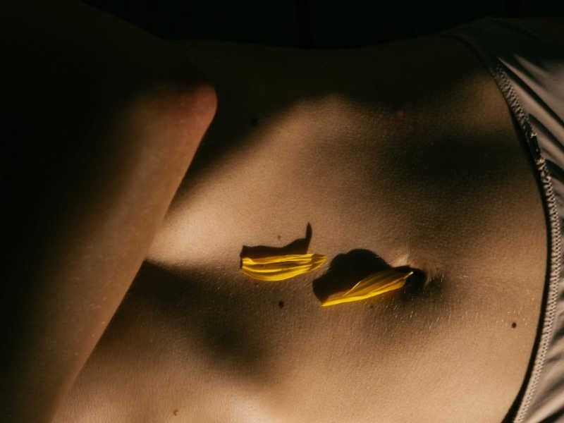 a dimly lit image of a person's stomach with two yellow flower petals