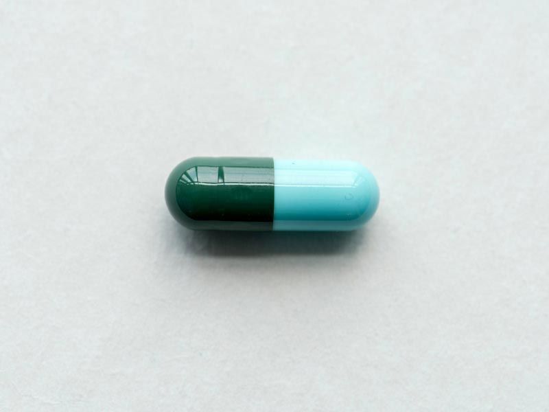 A green and blue capsule on a grey surface