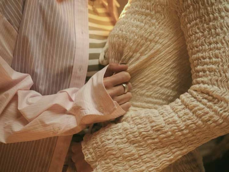 A close up of two people in an intimate embrace. One person tugging the other's shirt