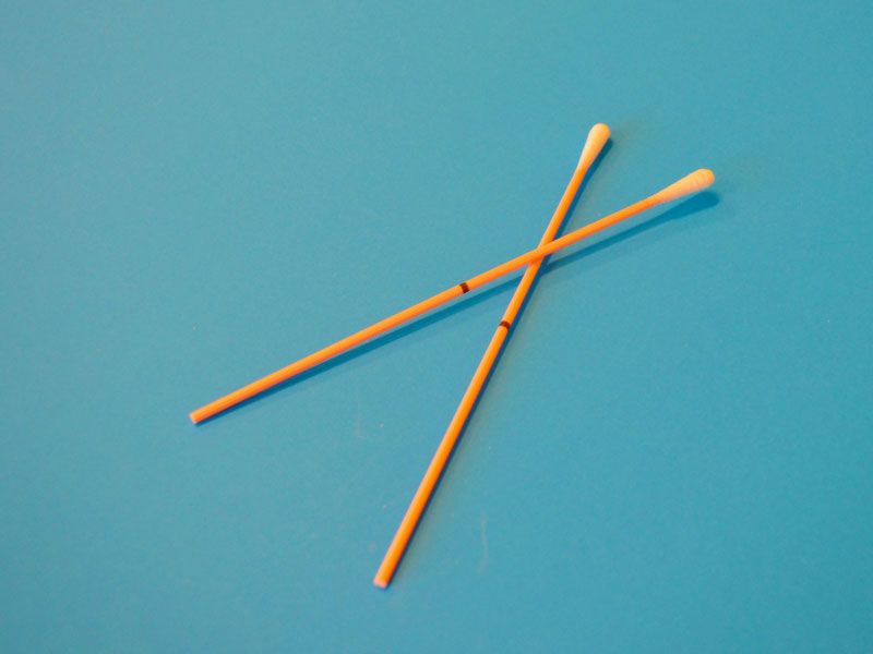 Orange test swabs on a teal-colored background