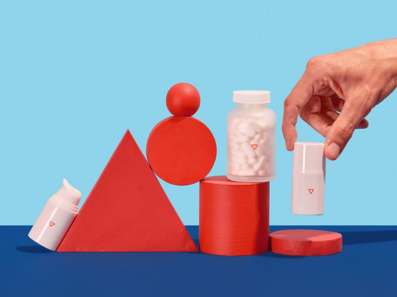 a man's hand picks up Wisp cold sore medications on a colorful geometric background