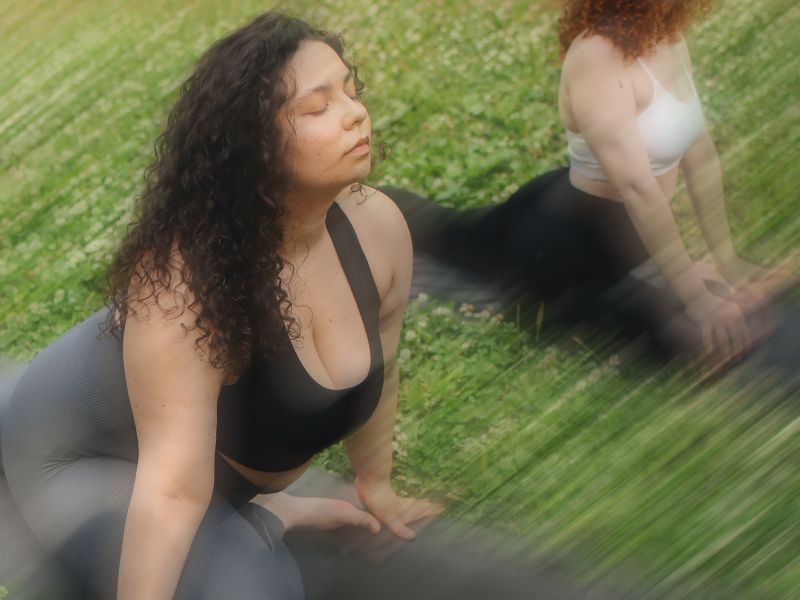 slightly blurry image of two women stretching in a grass field