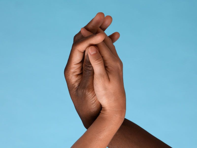 Two hands embracing in front of a blue background