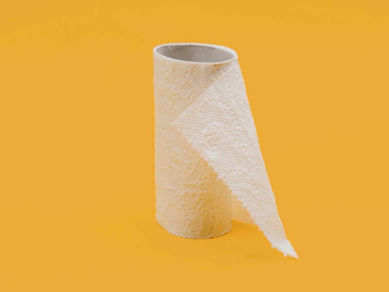 An almost empty toilet roll sitting on a yellow surface