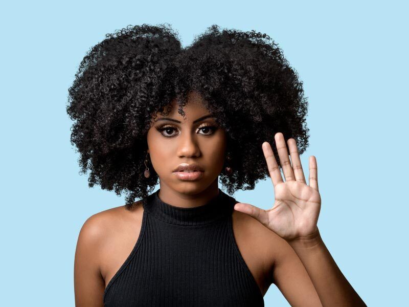 a woman holding up her hand in a stop motion against a blue background