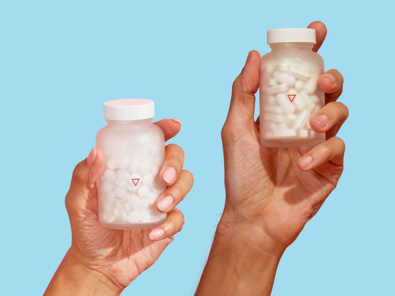 Two hands holding Wisp Valacyclovir and Acyclovir glass jars with a light blue background