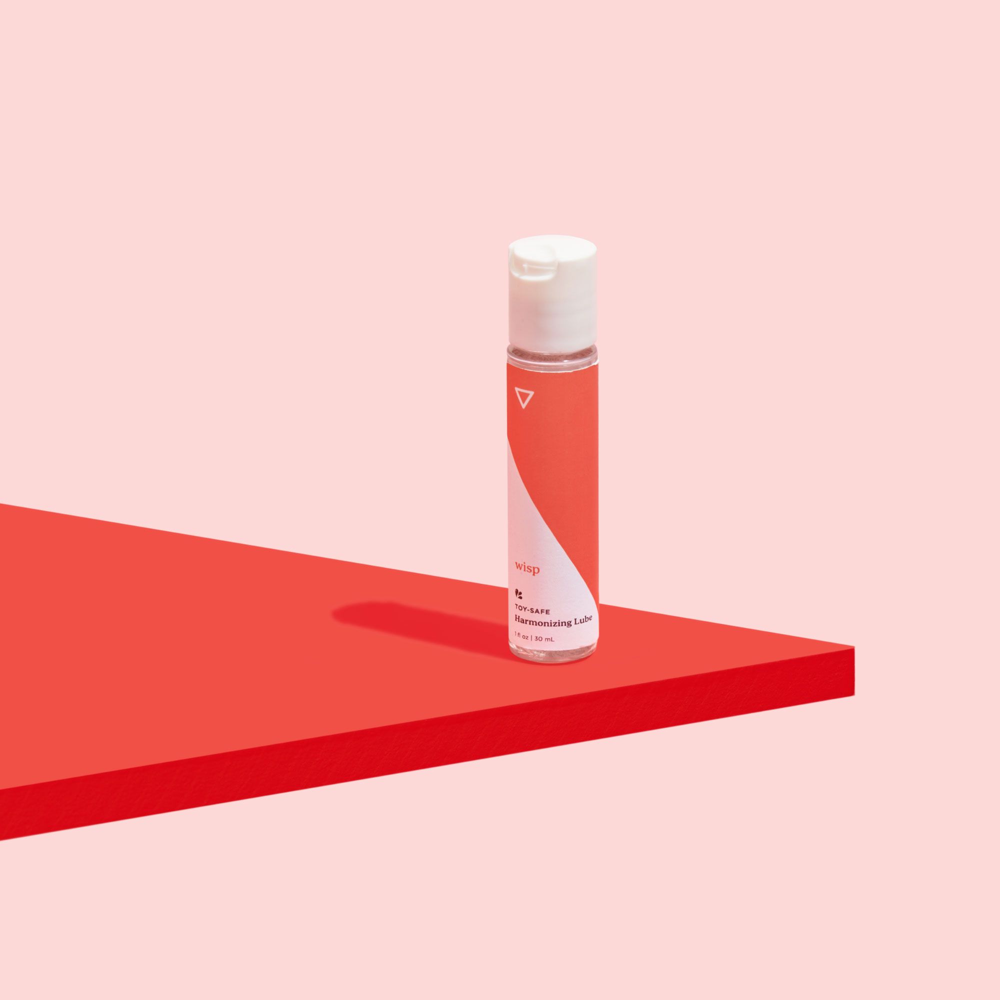 Wisp's Toy Safe Lube on a red surface, on a pink background