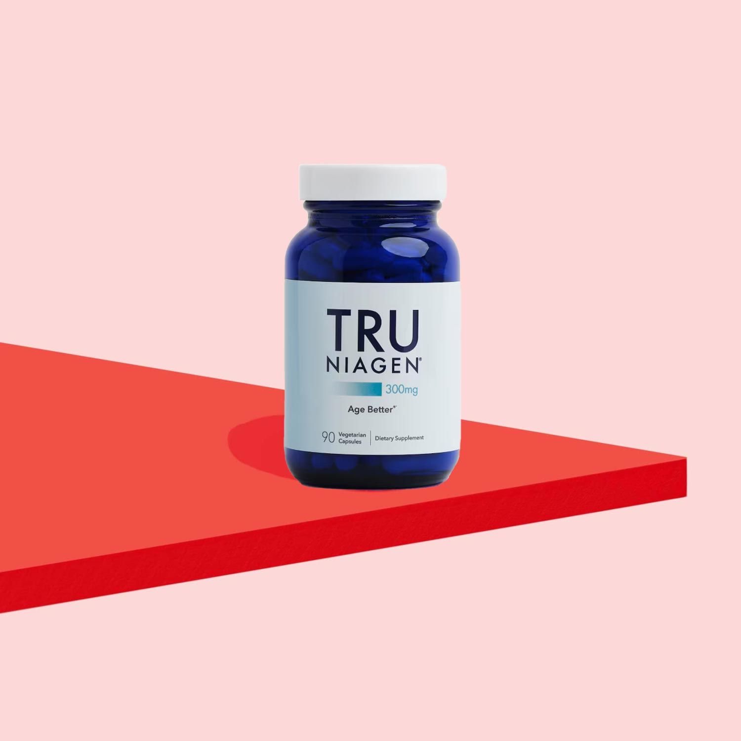 A Tru Niagen supplement bottle on a red surface with a pink background