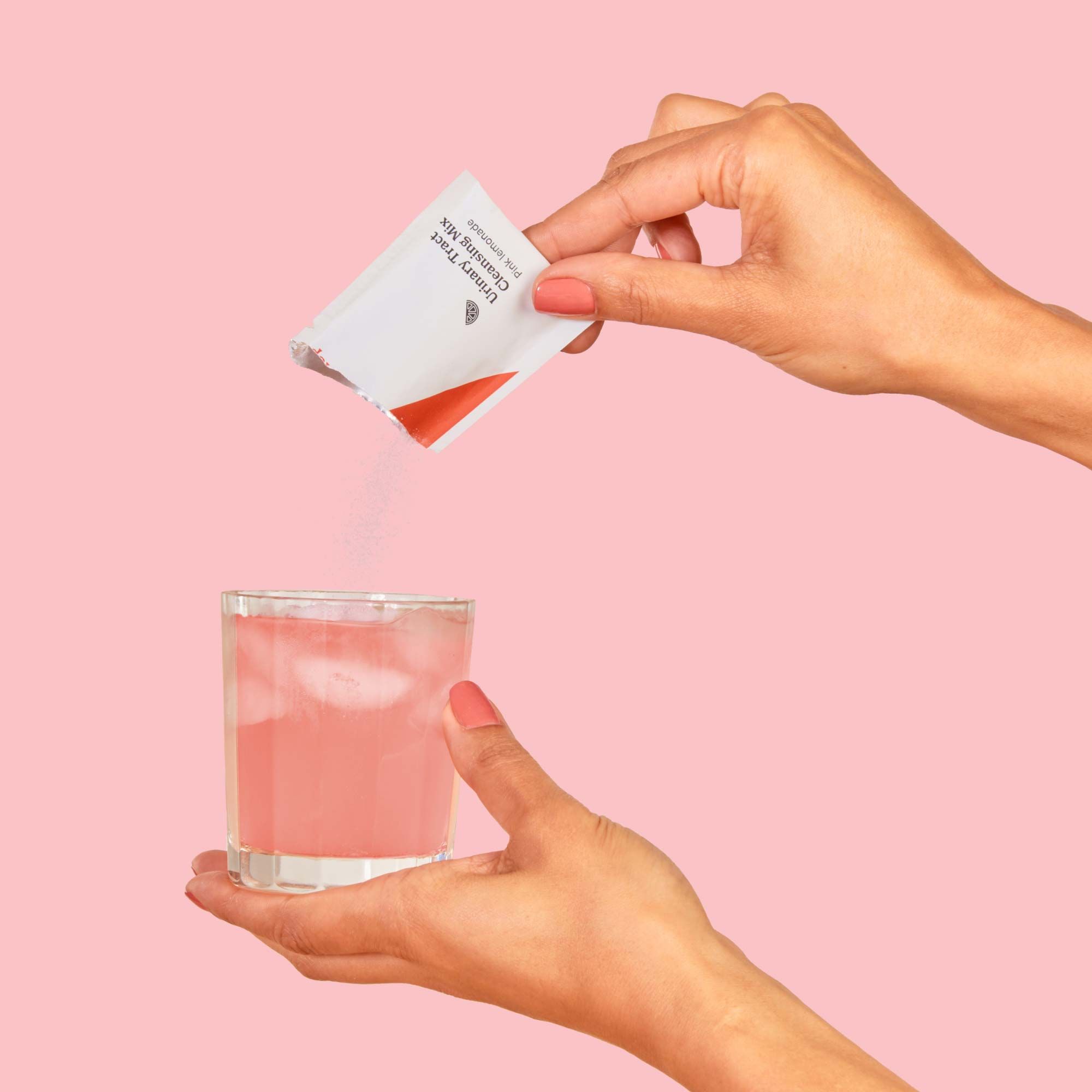 A woman's hand is pouring a packet of Wisp Urinary Tract Cleansing mix into a glass of water