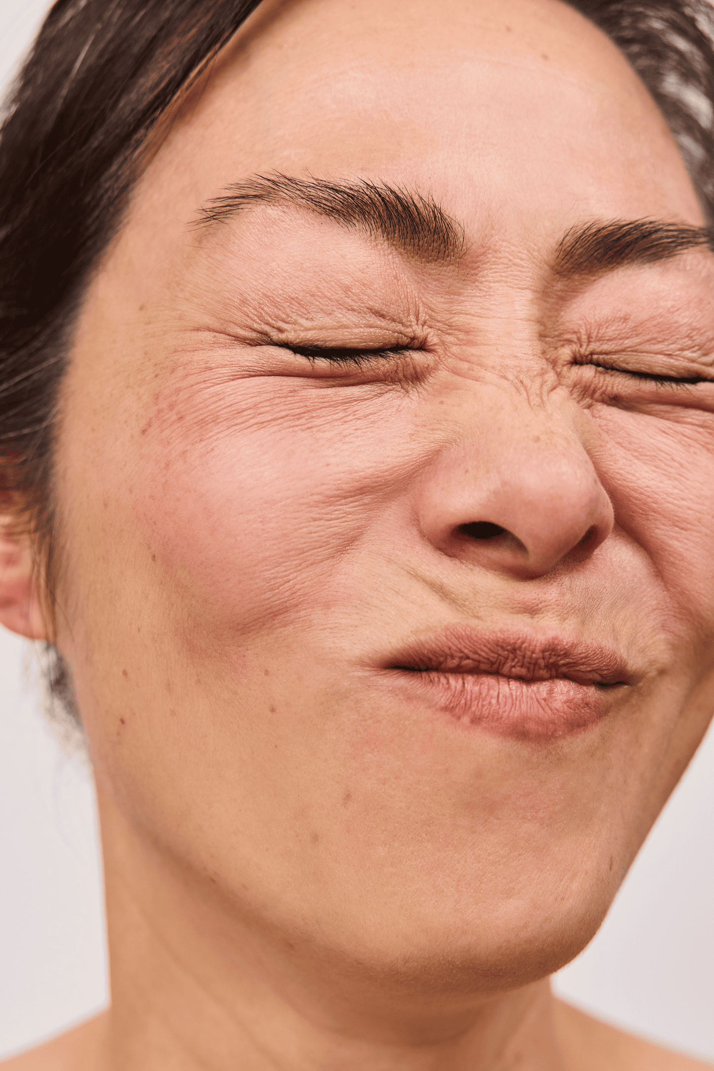 a woman smiling while scrunching her face