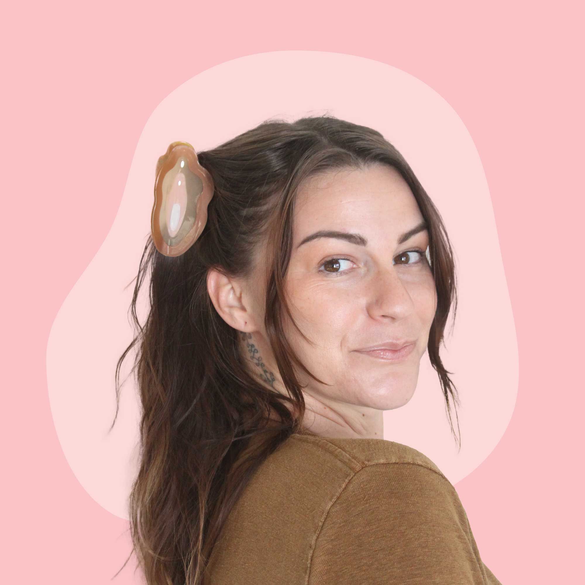 A woman with brown hair is wearing brown a brown vulva clip in her hair