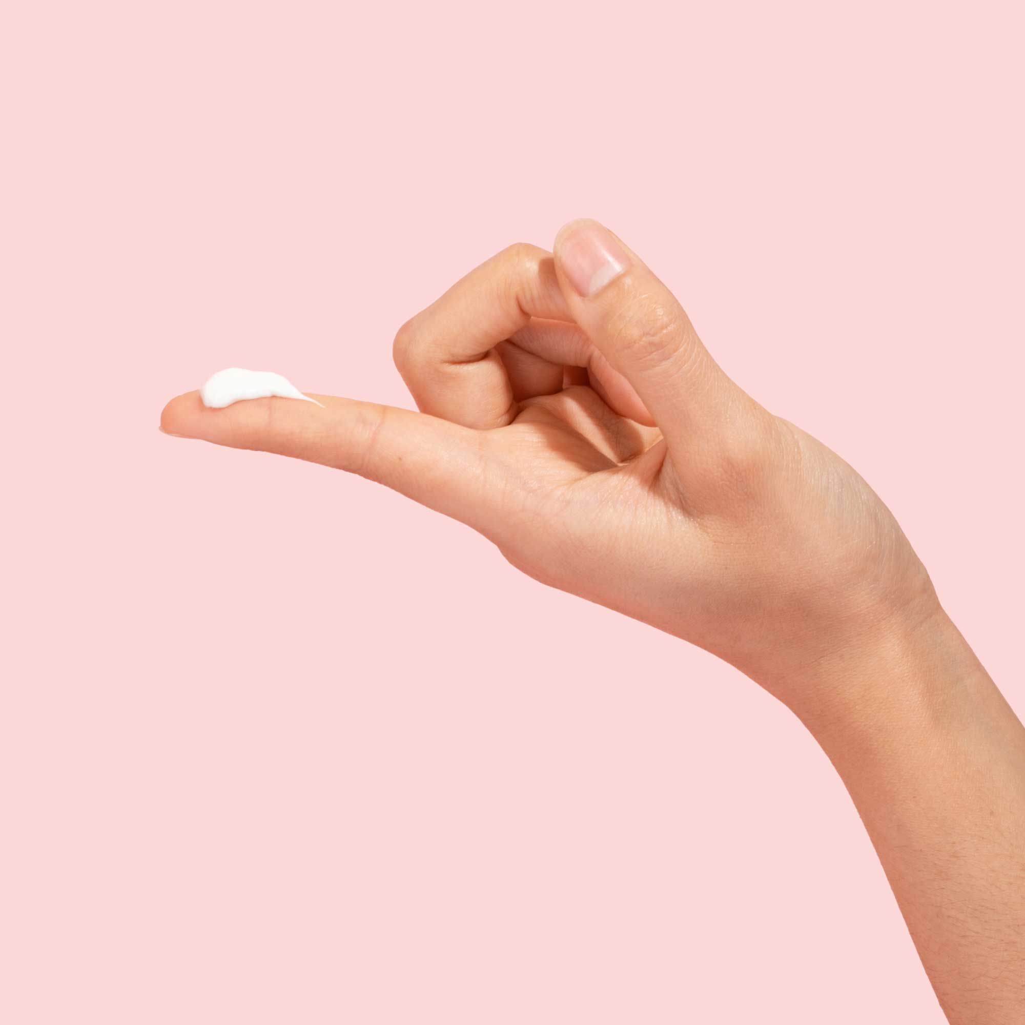 A woman's hand with Wisp Vulva Coco Cream on the index finger in front of a pink background