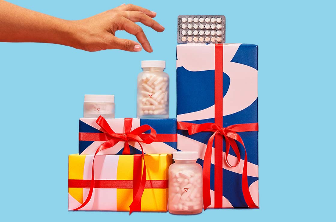 A woman's hand reaching for various Wisp products balanced on colorful gift wrapped boxes with a light blue background